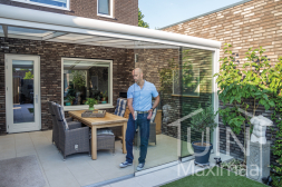 Moderne Gumax overkapping in mat wit met opaal polycarbonaat dak en glazen schuifdeuren